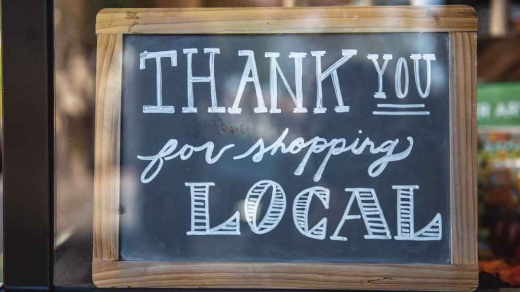 A creative chalkboard sign in a window with the words "Thank You for Shopping Local" written in various artistic styles, representing local link building.