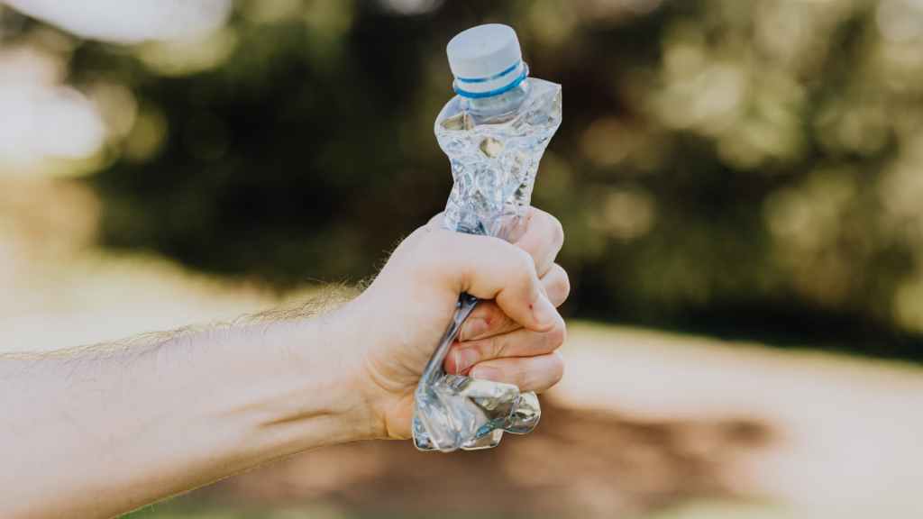 A hand compressing a plastic water bottle. Depicts the concept of image compression.