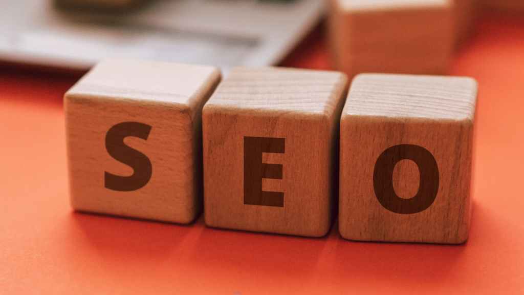 Wooden children's play blocks arranged to spell the words "SEO" on an orange desk. Symbolizing the focus of the article on the fundamental aspects of SEO.