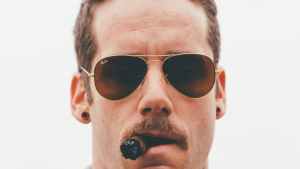 A man wearing aviator glasses exudes confidence as he chomps on a cigar. Symbolizing the crucial role of image in establishing website authority.